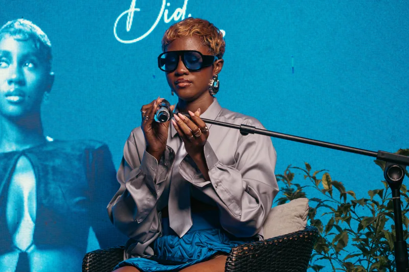 Speaker in sunglasses against a saturated blue backdrop