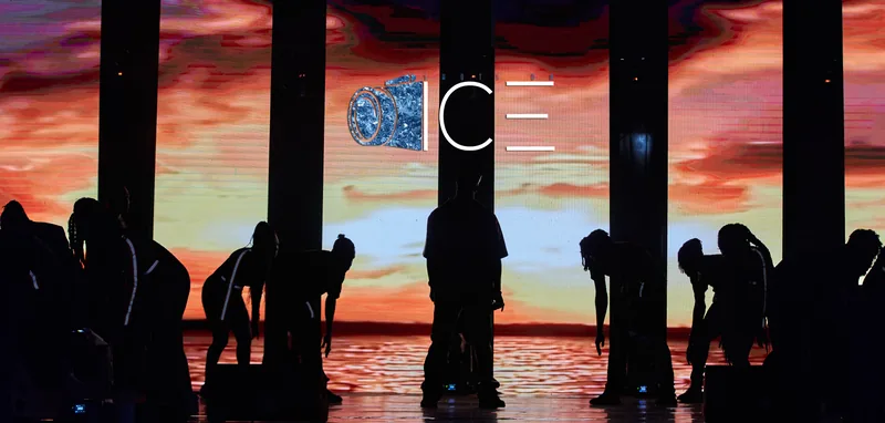 Crowd in silhouette against a red and orange stage screen